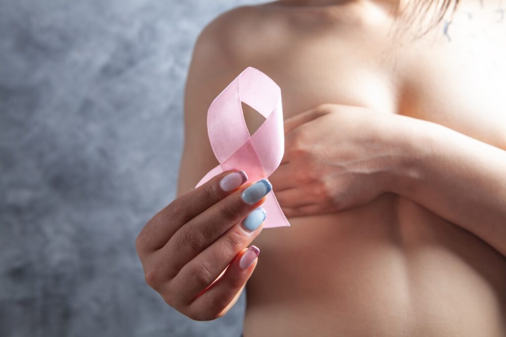 woman breast cancer awareness ribbon on grey background. healthcare concept