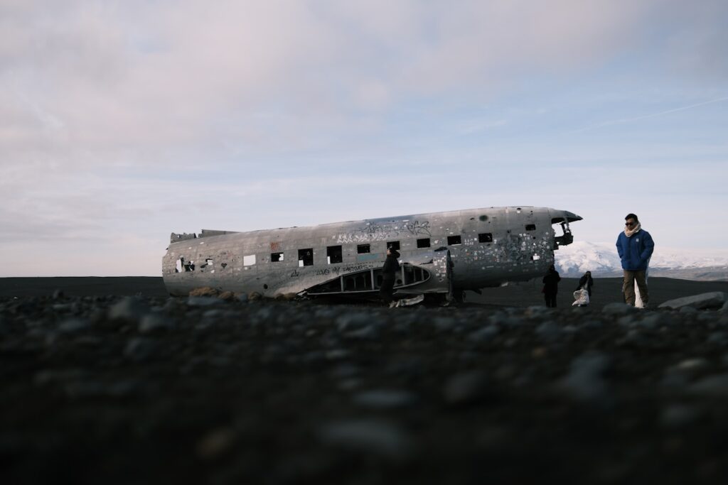 Two people stand by a crashed airplane wreckage.