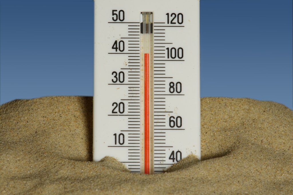 A thermometer in the sand with a blue sky in the background