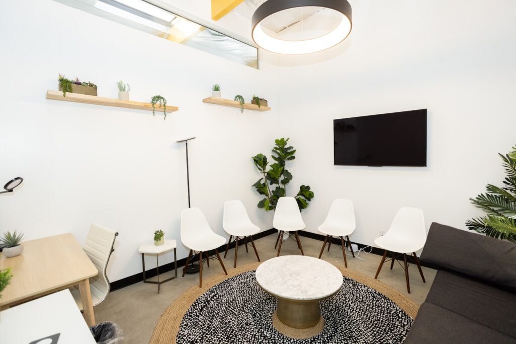 Modern waiting room with white chairs and plants.